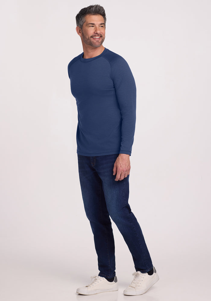 Smiling man in a Woolx Essential Tee • Final Sale - Starry Night, dark jeans, and white sneakers against a plain background.