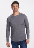 A man with short dark hair and stubble smiles while wearing a Woolx Essential Tee in Graphite Heather and blue jeans, posing against a plain white background. | Matthew is 6’, wearing a size L