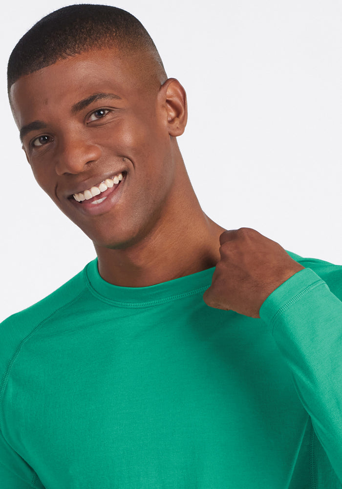 Man smiling in a Woolx Essential Tee - Jungle, holding the collar against a plain background.