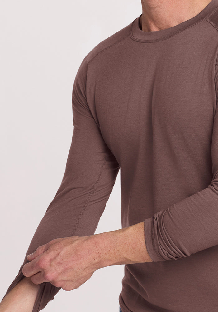 Person wearing a Woolx Essential Tee - Peppercorn, pulling up their left sleeve against a light background.