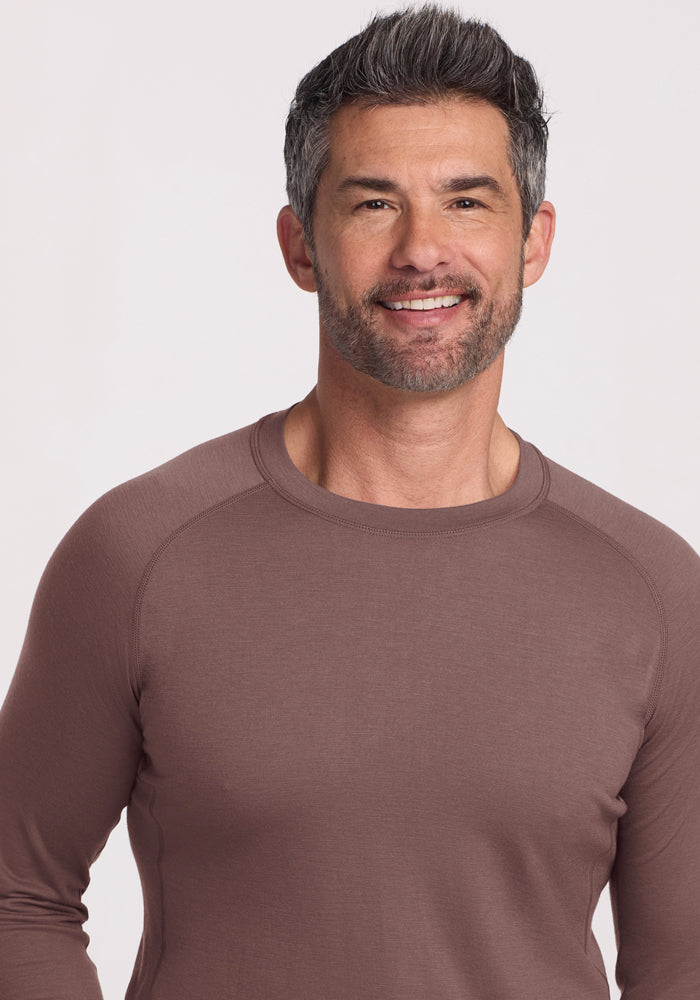 Smiling man with short dark hair and a beard wearing the Woolx Essential Tee in Peppercorn against a light background.
