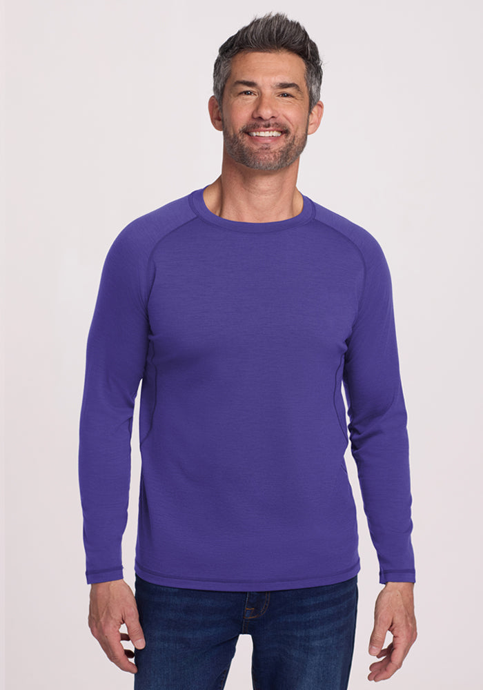 Smiling man in a Woolx Essential Tee - Berry Indigo, enjoying its temperature-regulating comfort against a light background. | Matthew is 6’, wearing a size L
