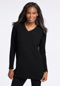 A person with long hair smiles while wearing the Evie Tunic - Black from Woolx. The temperature-regulating Merino wool fabric ensures comfort, accentuated by the plain white background.