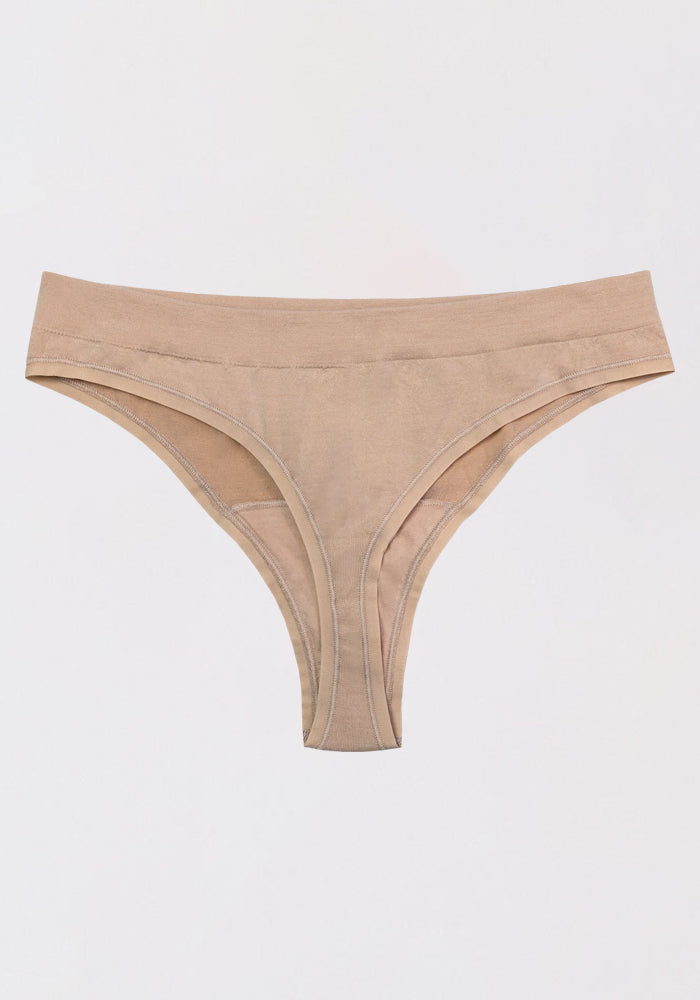 The Woolx Farrah Thong is displayed flat on a white background, highlighting its beige color, seamless design, and smooth waistband for comfortable wear.