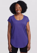 Smiling woman in Woolx Gabi Tunic Top - Berry Indigo and black shorts, standing against a white background. | Pechaz is 5’4”, wearing a size S
