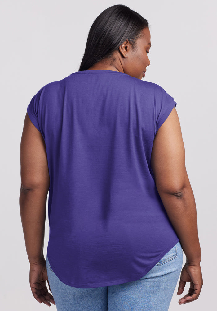 A woman wears the Woolx Gabi Tunic Top in Berry Indigo and light blue jeans, shown from the back.