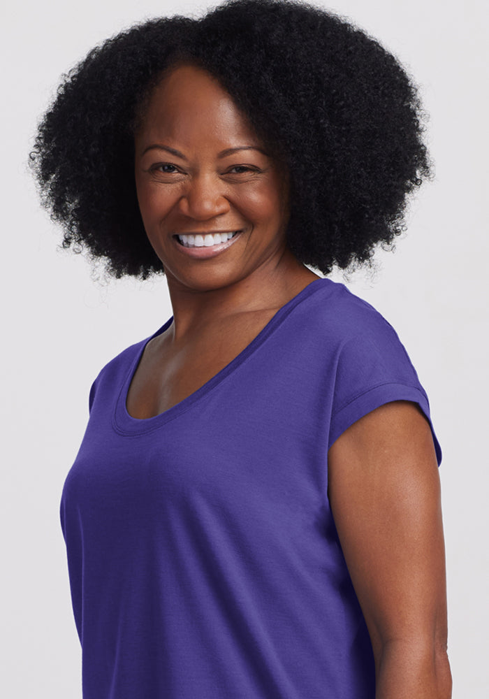 Smiling woman in Woolx Gabi Tunic Top in Berry Indigo, standing against a plain light background.