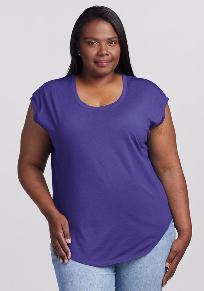 A woman wears the Woolx Gabi Tunic Top in Berry Indigo with light blue jeans, facing the camera and smiling slightly. | Le’Quita is 5’11”, wearing a size XL