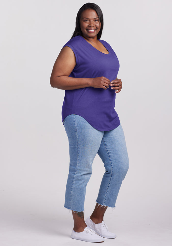 Smiling woman wears the Woolx Gabi Tunic Top in Berry Indigo with light blue jeans and white sneakers.