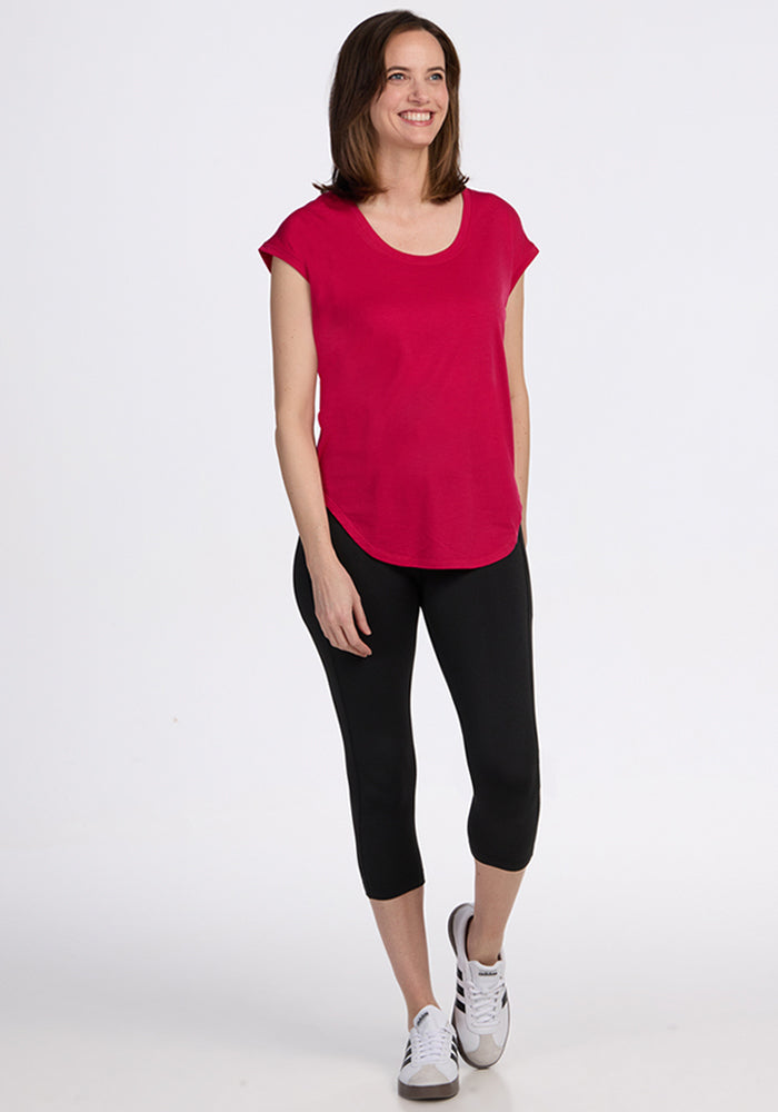 Woman wearing the Woolx Gabi Tunic Top in Poppy Spark, black capri leggings, and white sneakers, smiling.