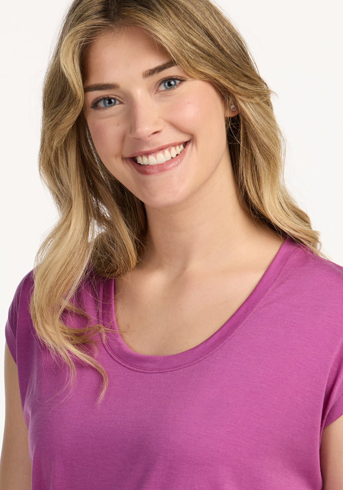 Blonde woman wearing Woolx Gabi Tunic Top in Purple Wine, standing against a plain light background.