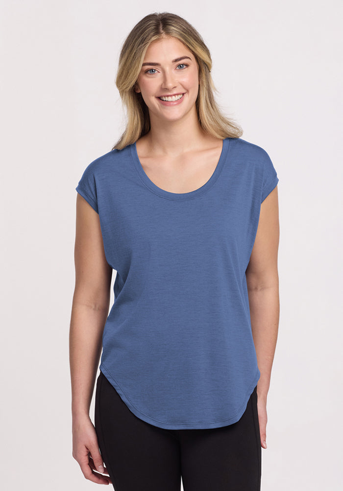 Smiling woman wears Woolx Gabi Tunic Top in Skyline and black pants, standing against a plain light background.