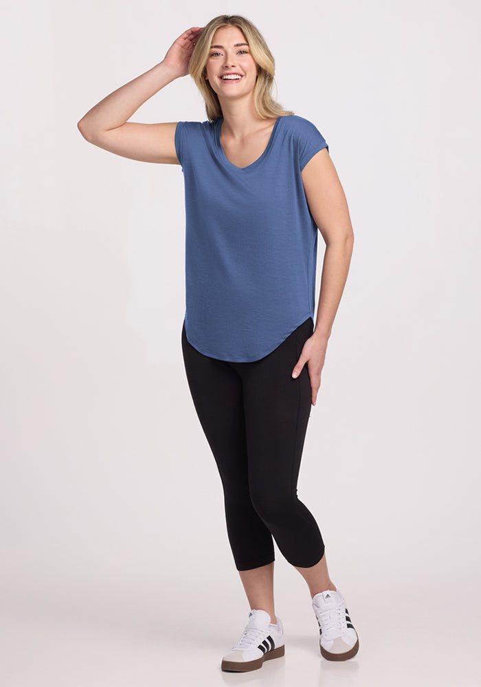 Smiling woman wears the Woolx Gabi Tunic Top in Skyline, paired with black leggings and white sneakers.