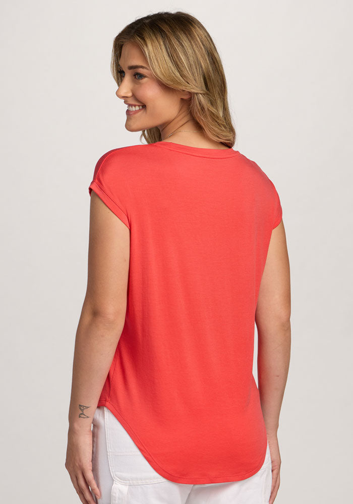 Woman smiles in the Woolx Gabi Tunic Top - Hibiscus, shown from the back with white pants against a light background.