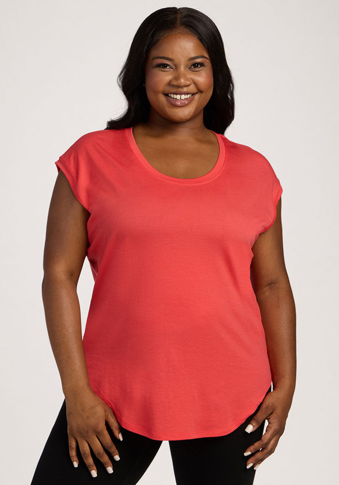 Smiling woman wears Woolx Gabi Tunic Top in Hibiscus with black pants, standing against a plain light background. | Sapphire is 5’8”, wearing a size XL