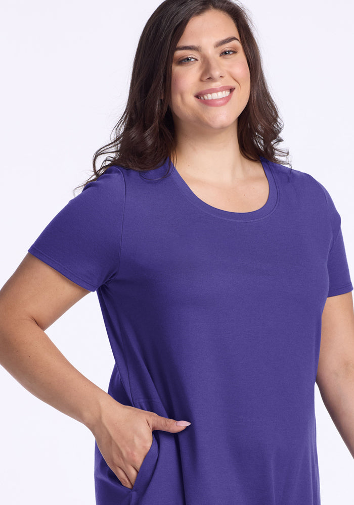 Smiling woman with long brown hair wears the Woolx Georgie Dress - Berry Indigo, one hand in her pocket.