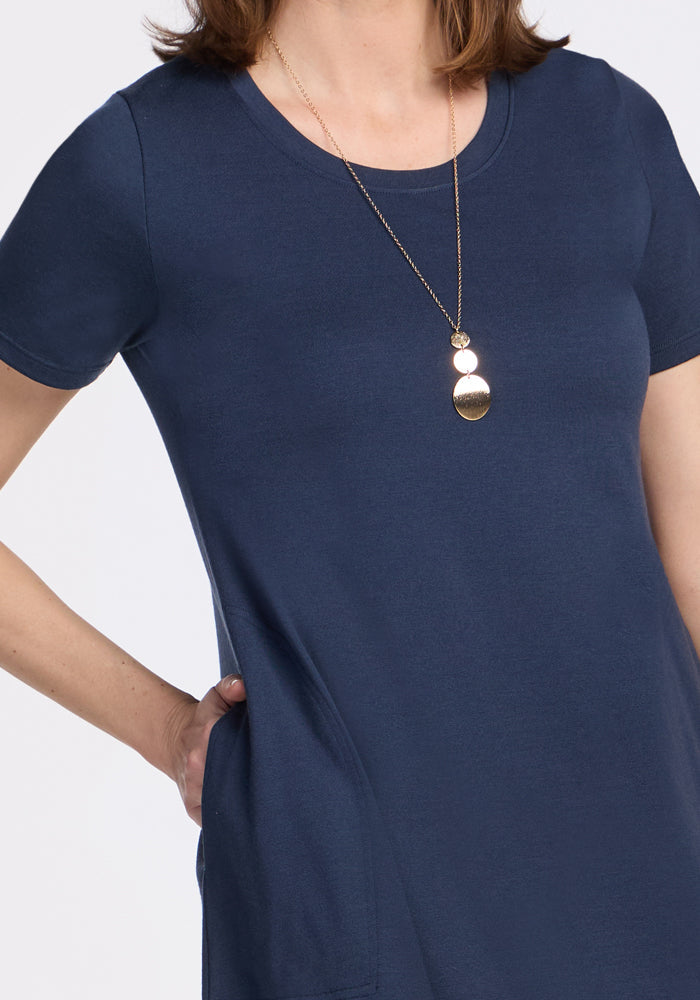 Woman in Woolx Georgie Dress • Final Sale - Deep Navy, hand in pocket, with gold pendant on white background.