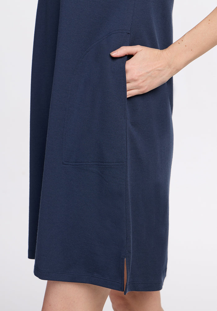 A person in the Woolx Georgie Dress • Final Sale - Deep Navy, with one hand in a large side pocket and a hem slit.