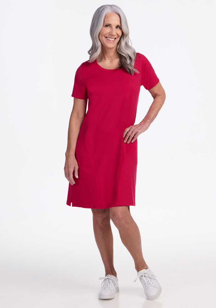 Smiling woman in Woolx Georgie Dress, Poppy Spark, final sale, with white sneakers against a white background.