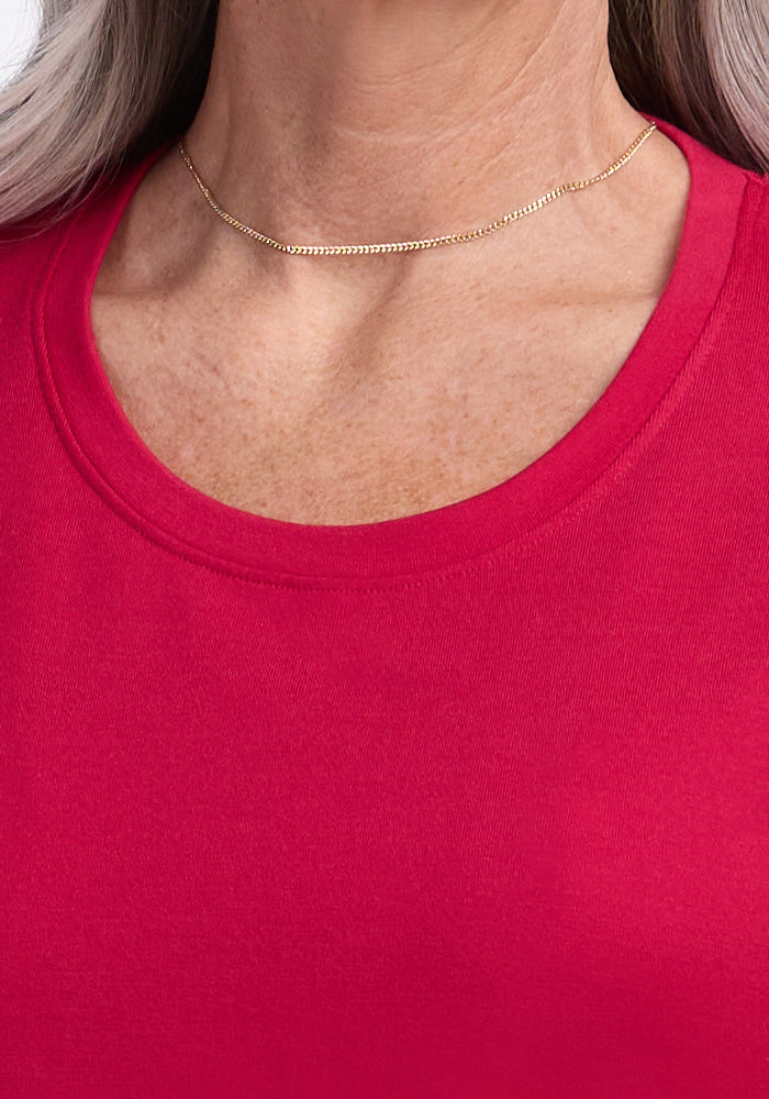 A person wearing the Woolx Georgie Dress in Poppy Spark and a thin gold necklace.