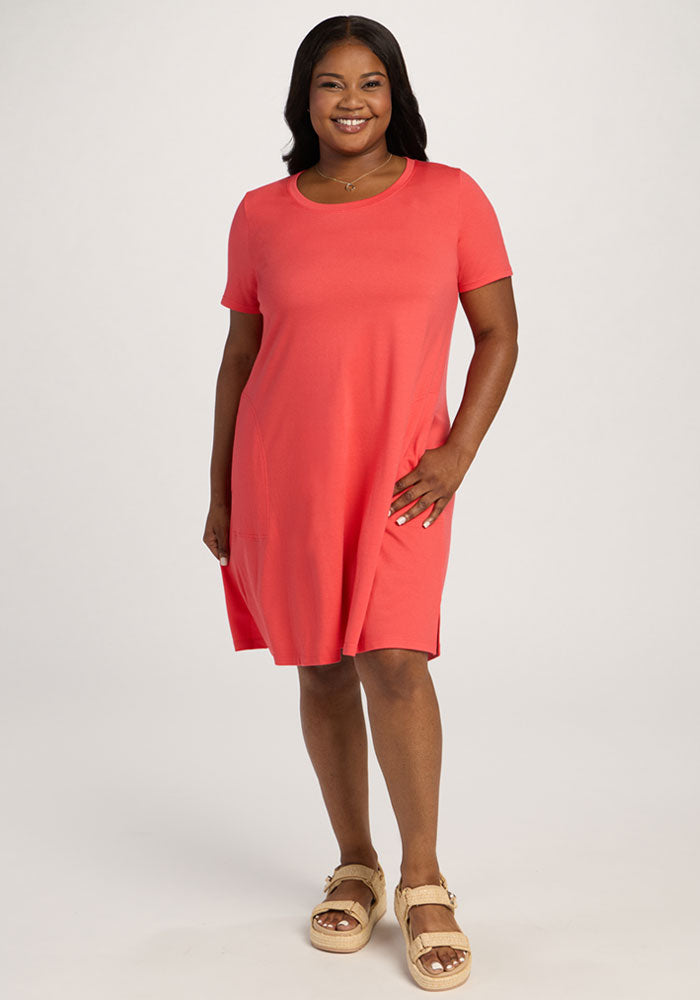 Smiling woman in the Woolx Georgie Dress - Hibiscus and sandals stands against a plain light background. | Sapphire is 5’8”, wearing a size XL