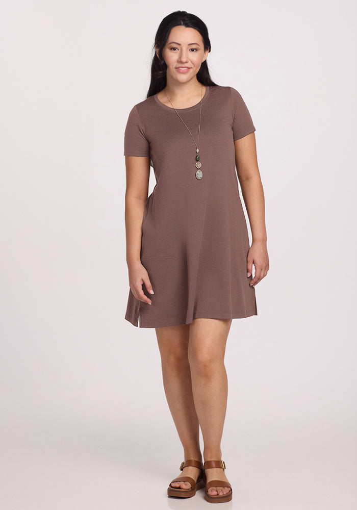 Woman in Woolx Georgie Dress - Peppercorn, necklace, and sandals, standing and smiling against a plain background.