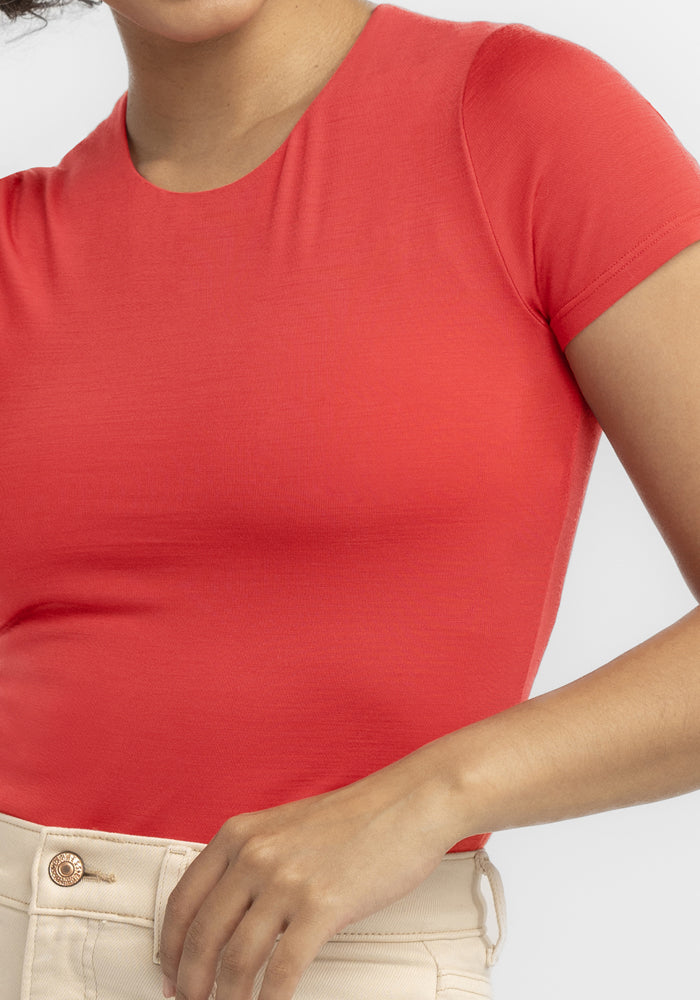 Woman in the Woolx Gracie Bodysuit - Hibiscus, paired with high-waisted beige pants, shown shoulders to hips.