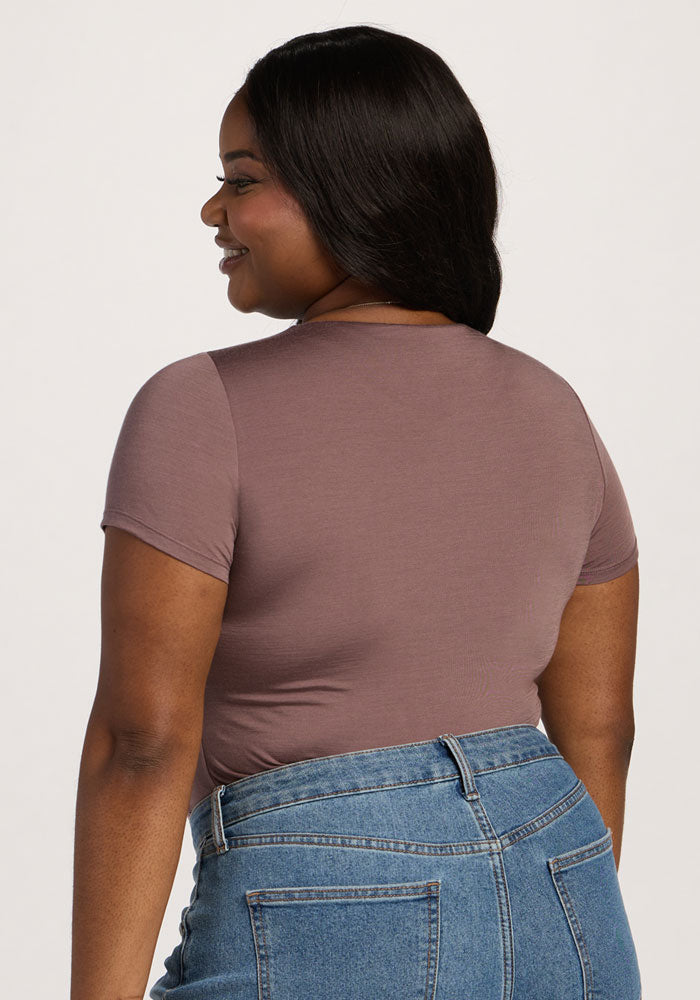 Woman with long dark hair wearing the Woolx Gracie Bodysuit in Peppercorn and high-waisted blue jeans, shown from the back.