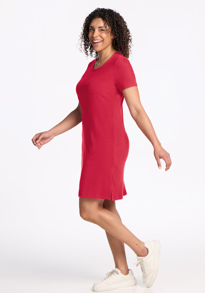 Woman smiling in the Woolx Harlowe Ribbed Dress in Berry Ice Pop with white sneakers, against a white background.