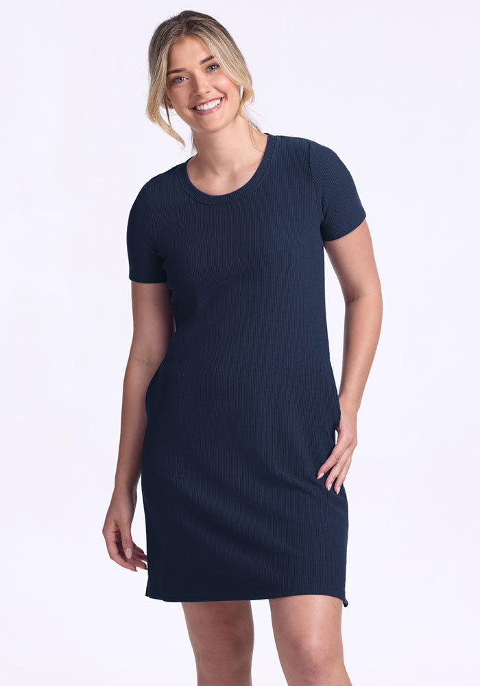 Smiling woman in the Woolx Harlowe Ribbed Dress in Deep Navy stands against a plain white background.