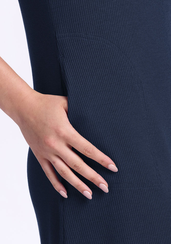 A manicured hand rests on the hip of a person in the Woolx Harlowe Ribbed Dress in Deep Navy.