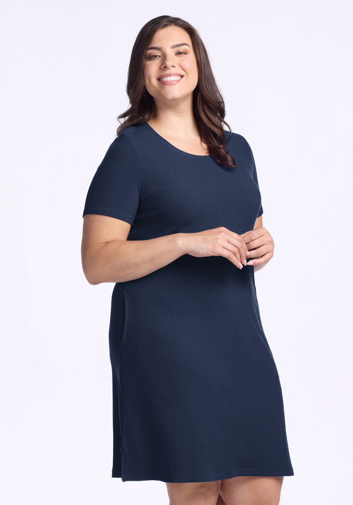 Smiling woman with long brown hair wears the Woolx Harlowe Ribbed Dress in Deep Navy, standing against a white background.