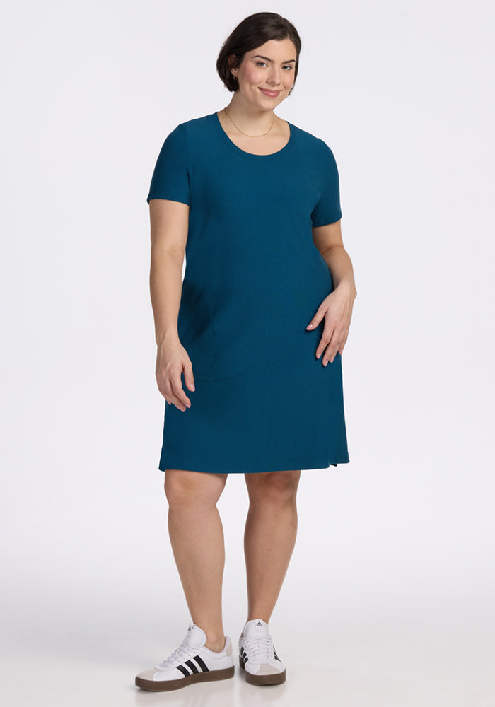 Woman smiling in the Harlowe Ribbed Dress in Moroccan Blue by Woolx, standing against a plain white background.