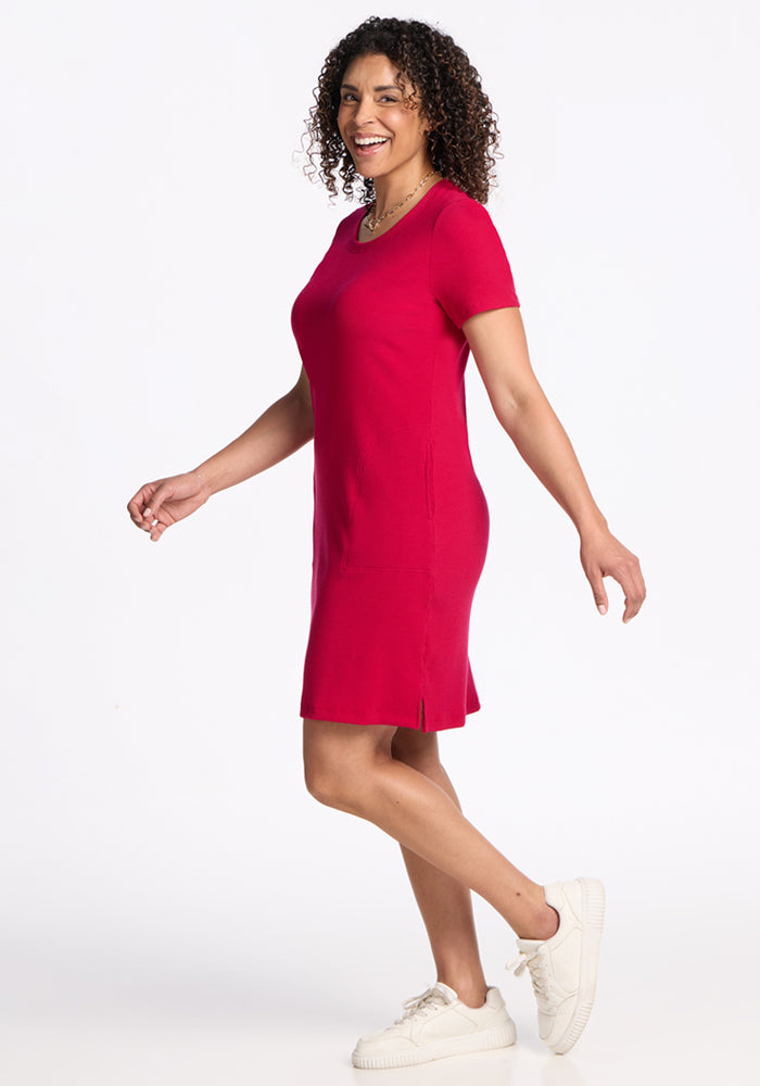 Woman smiles in the Woolx Harlowe Ribbed Dress in Poppy Spark, standing against a plain white background.