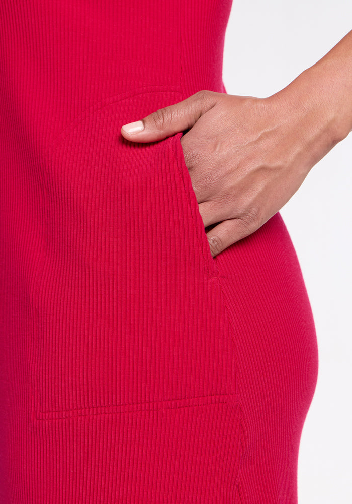A hand in the pocket of the Woolx Harlowe Ribbed Dress in Poppy Spark, shown against a white background.