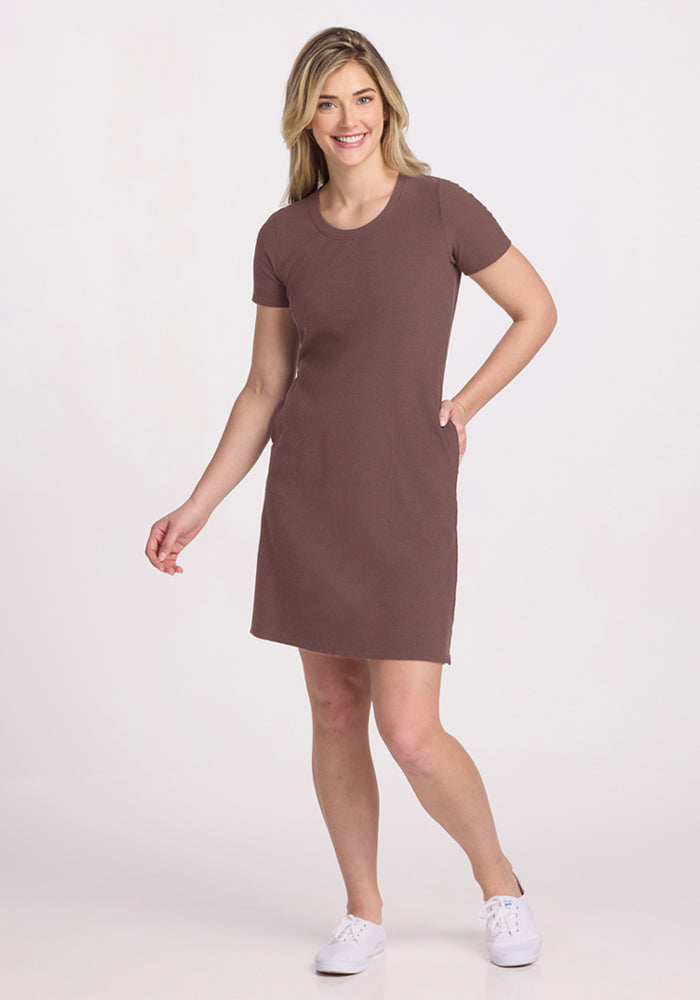 Woman in a Woolx Harlowe Ribbed Dress - Peppercorn and white sneakers, smiling against a plain light background. | Ariana is 5'11", wearing a size S