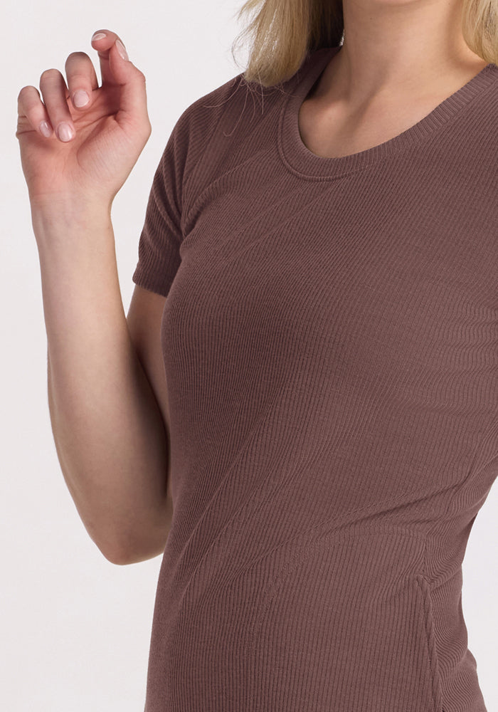 A woman in the Woolx Harlowe Ribbed Dress in Peppercorn poses with her hand up against a light background.