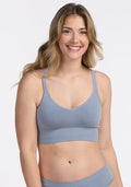 A smiling woman with long, wavy blonde hair models the Woolx Hayden Bra in Bluebell with matching bottoms, standing against a plain white background. | Ariana is 5'11", wearinng a size S