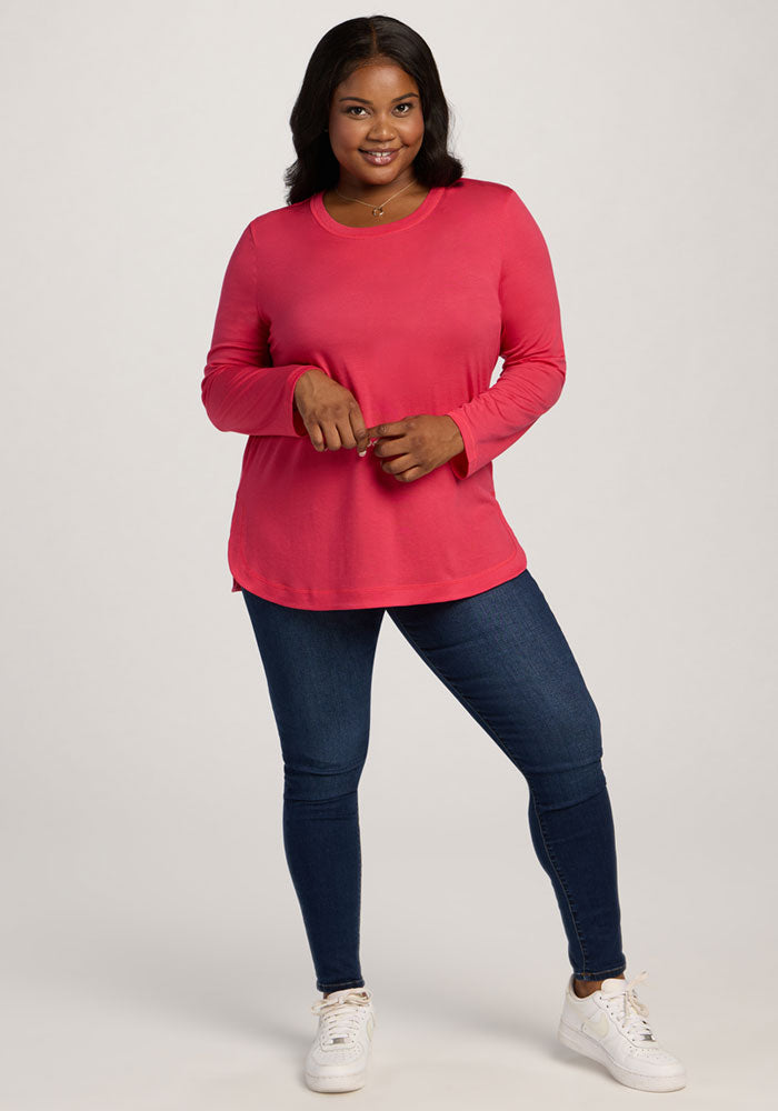 Woman in a Woolx Hazel Tunic - Berry Ice Pop, dark blue jeans, and white sneakers, smiling at the camera.
