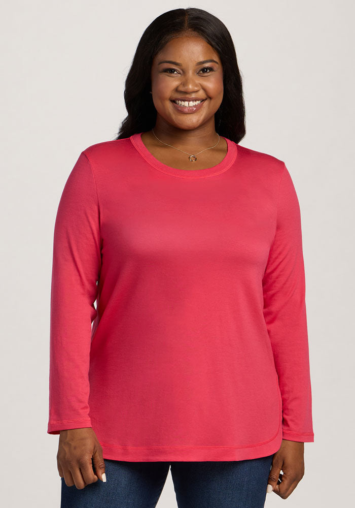 Smiling woman in Woolx Hazel Tunic - Berry Ice Pop and blue jeans, standing against a light background. | Sapphire is 5’8”, wearing a size XL