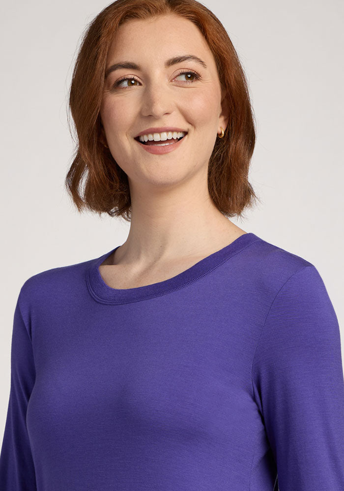Woman with short auburn hair wearing the Woolx Hazel Tunic in Berry Indigo, smiling and looking to the side.