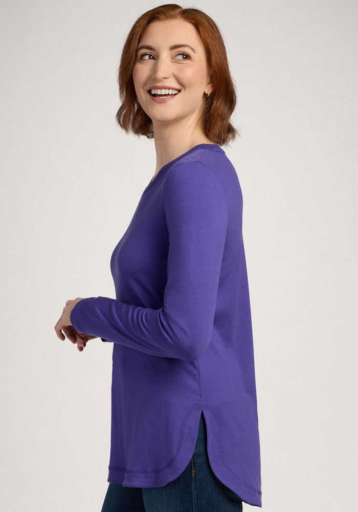 Smiling woman with shoulder-length red hair wears the Woolx Hazel Tunic in Berry Indigo, standing sideways.