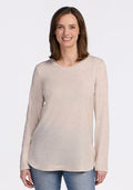 A woman with straight brown hair smiles at the camera, modeling the Woolx Hazel Tunic in Cream Heather with blue jeans. She stands against a white background, highlighting the tunic's temperature-regulating merino wool fabric. | Jessica is 5’10”, wearing a size S