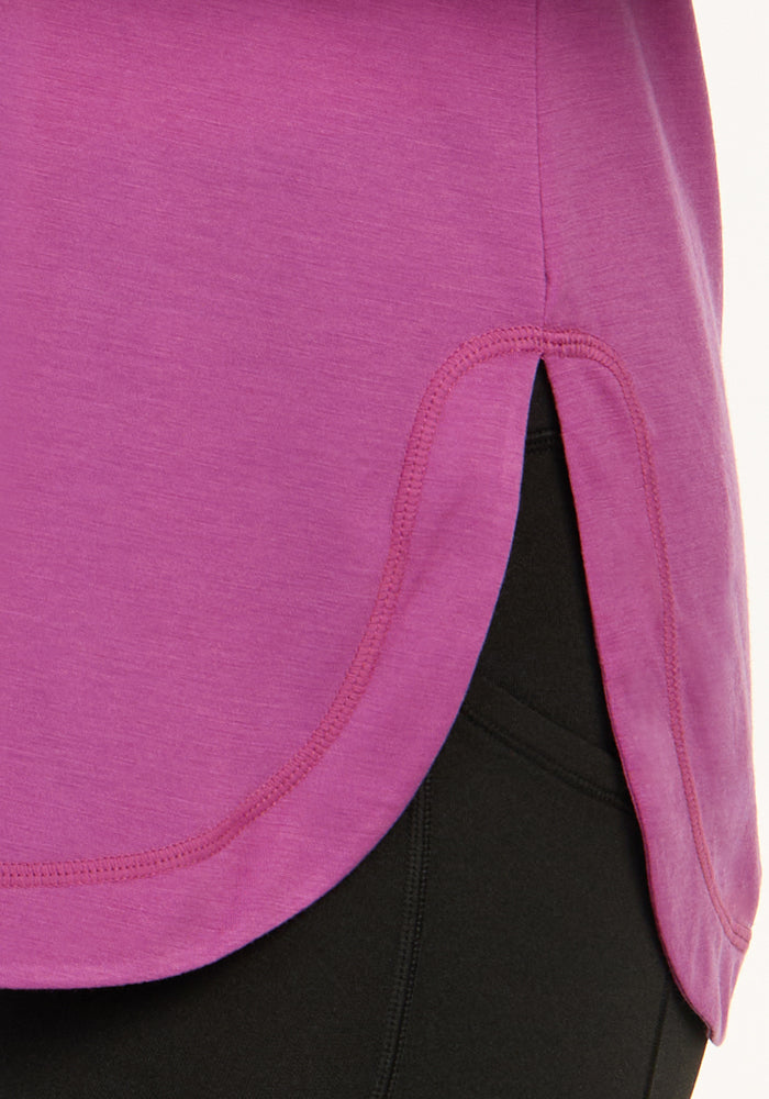 Close-up of the Woolx Hazel Tunic in Purple Wine, lightweight merino wool, curved hem, over black pants.