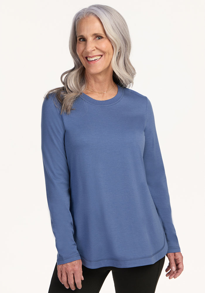 Smiling woman in a blue Woolx Hazel Tunic • Final Sale - Skyline, with long gray hair, against a light background.
