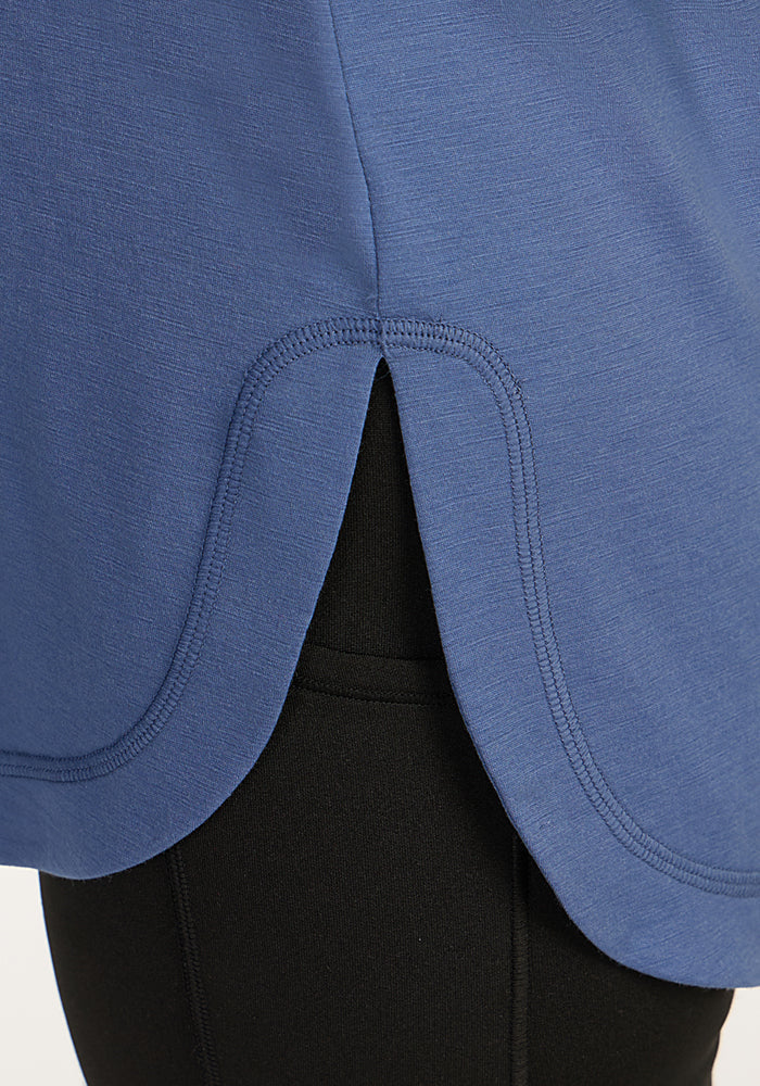 Close-up of the Woolx Hazel Tunic in Skyline, featuring a curved hem and side slit, styled over black pants.