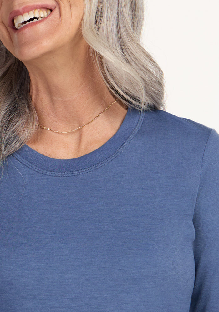 Smiling older woman wears the Woolx Hazel Tunic in Skyline blue with a delicate gold necklace. Final Sale.