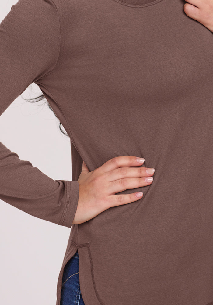 A person in a Woolx Hazel Tunic in Peppercorn rests their hand on their hip, revealing blue jeans.