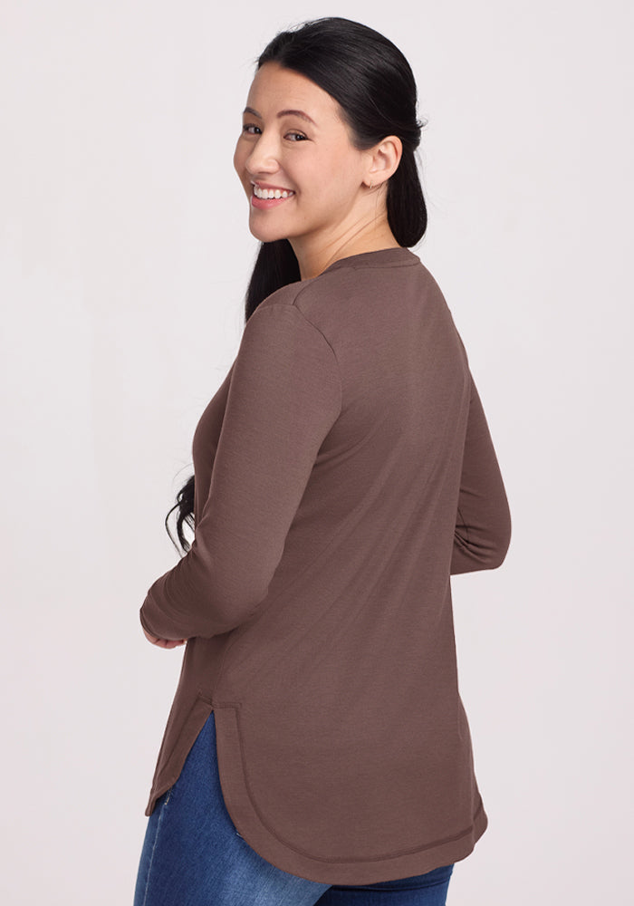 Woman with long dark hair smiles in a Woolx Hazel Tunic - Peppercorn, wearing blue jeans against a light background.