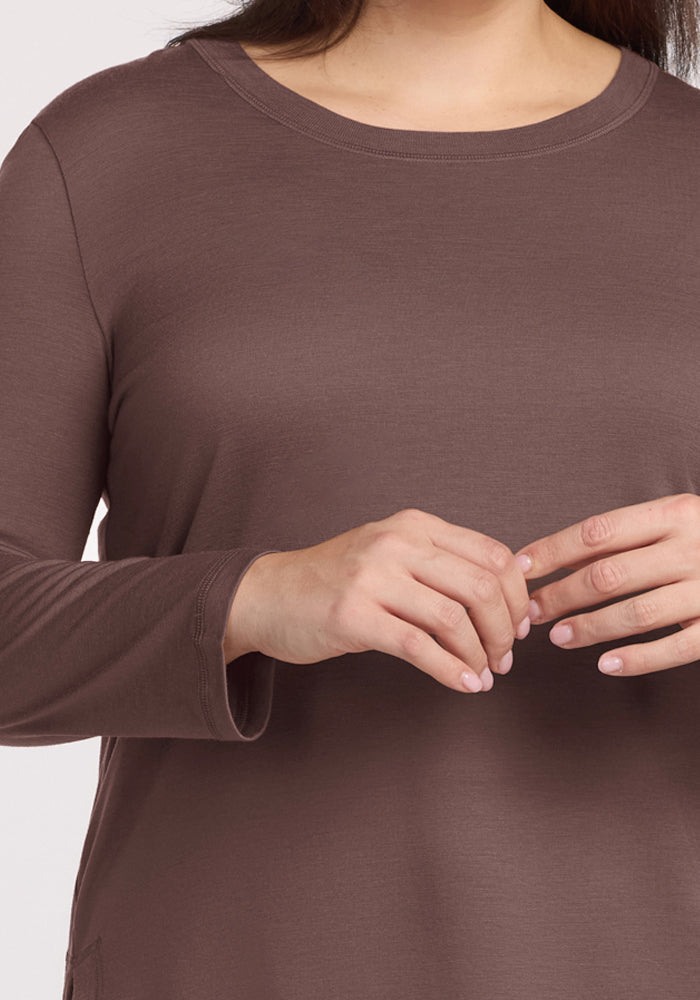 A person wears the Woolx Hazel Tunic - Peppercorn, hands clasped at chest height, shown from shoulders to waist.